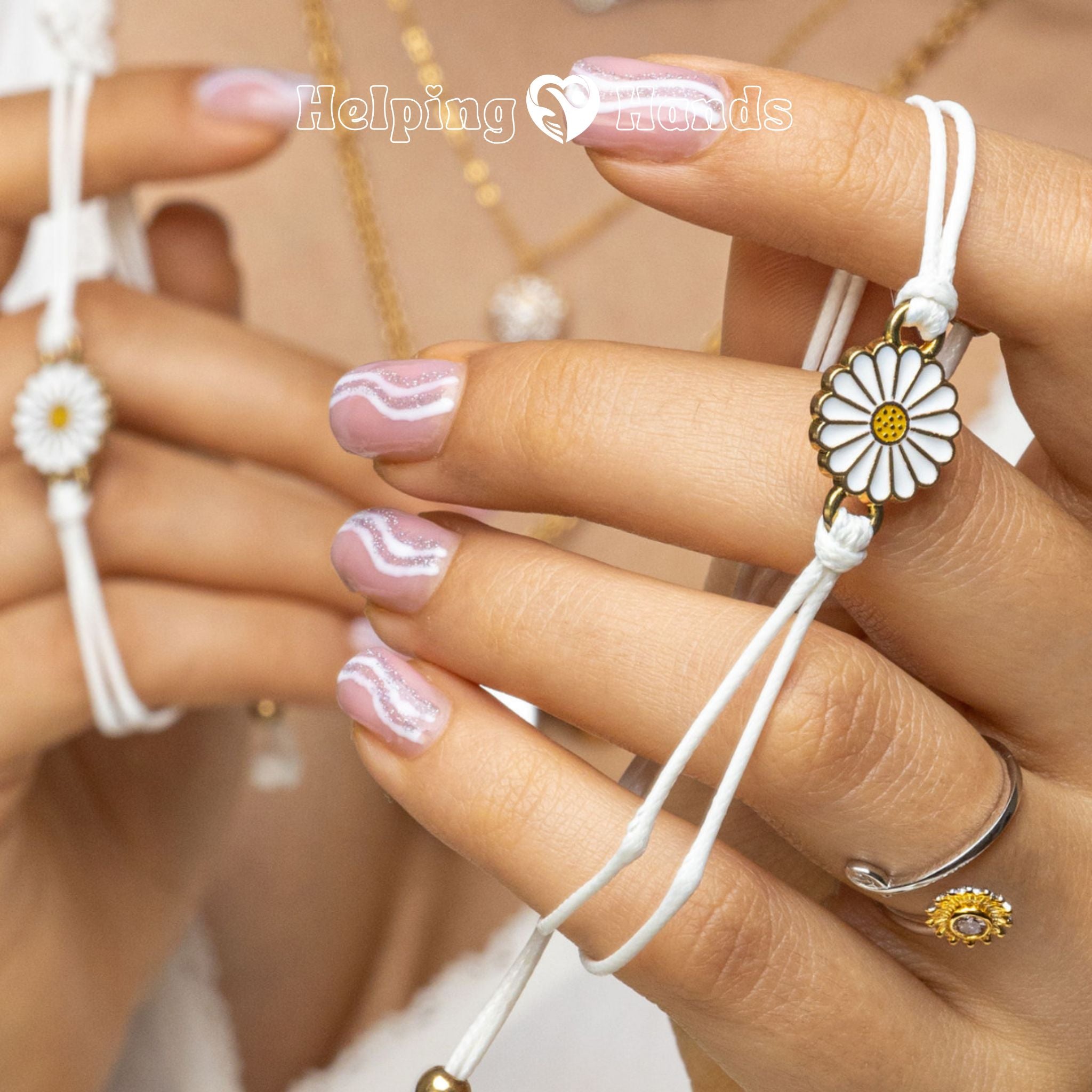 Close-up of hands wearing white bracelets with daisy flower designs, against a blurred background.