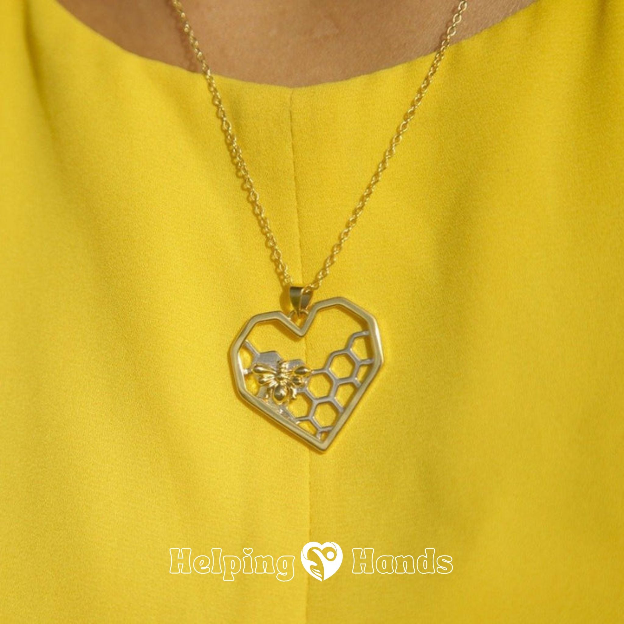 Gold necklace with a heart-shaped pendant featuring a honeycomb design on a yellow background.