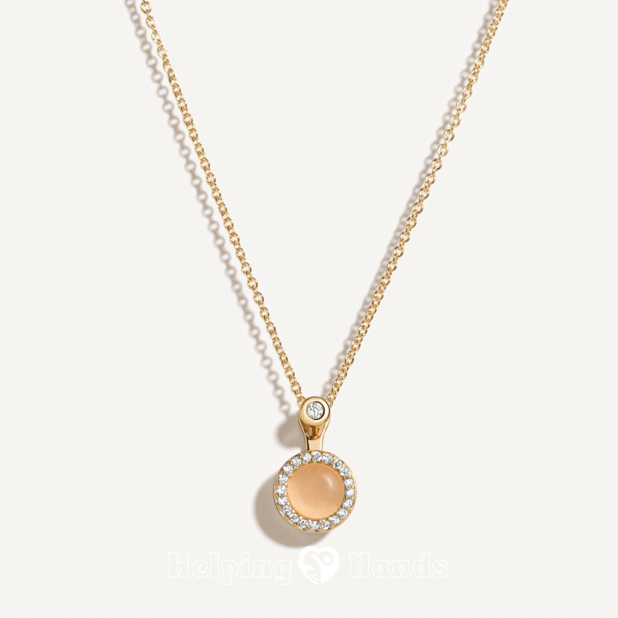 Gold necklace with a round pendant on a light gray background